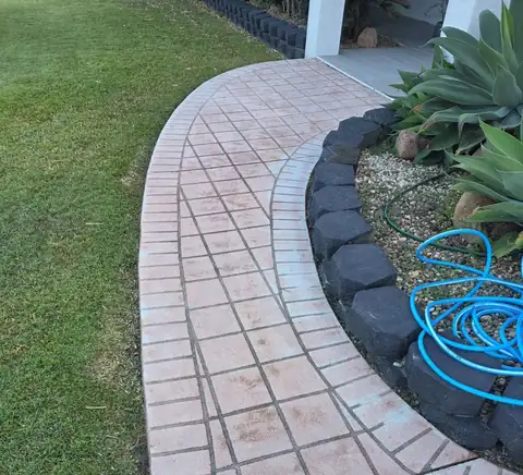 Before: a curved terracotta paver path beside a garden bed